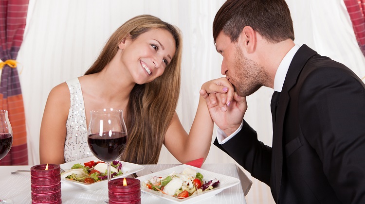 Man kissing a woman's hand at a romantic dinner