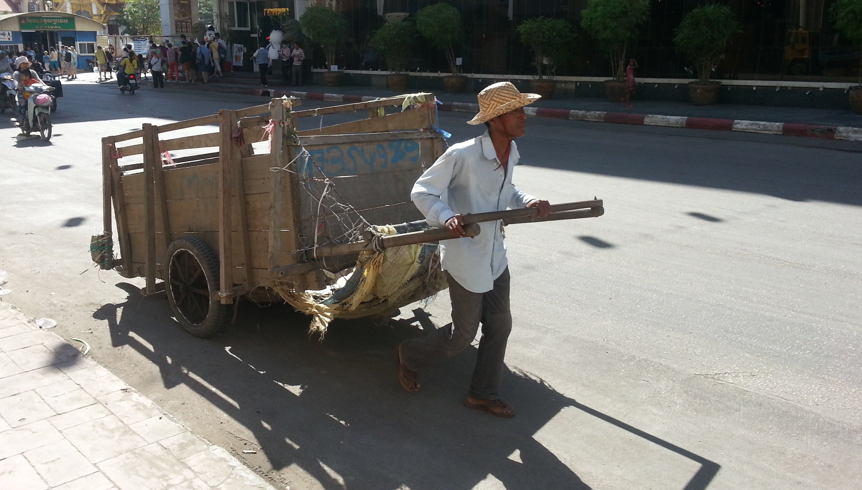 Cambodia man pulling rubbish cart on hot street